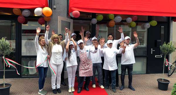 Het team van Da Nina zwaait voor de deur van het restaurant op de openingsdag, met ballonnen en een rode loper