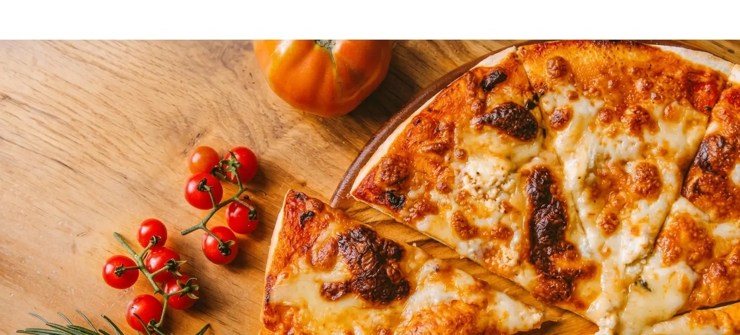 Vers gebakken pizza in punten op een houten plank, met cherrytomaten en rozemarijn ernaast
